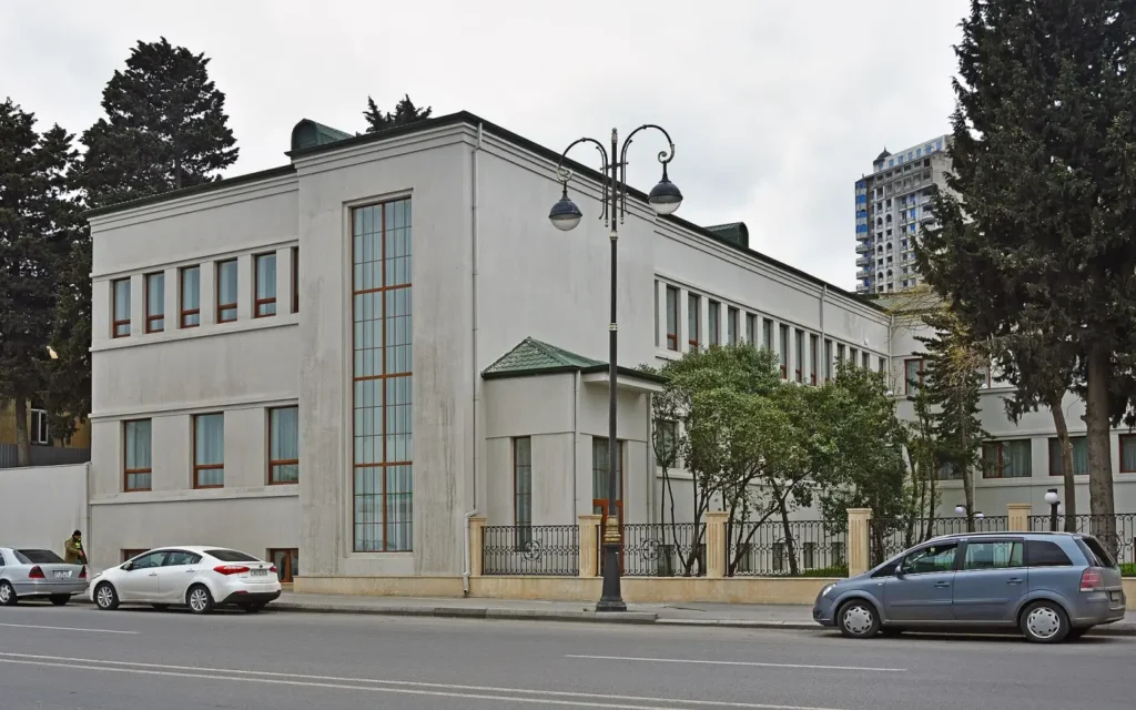 Traffic on Khatai Avenue in Baku in front of a white modernist building