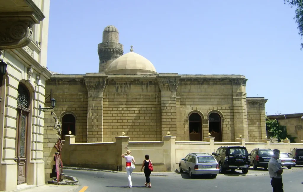 Dome and minaret of the Juma Mosque above a street in the Old City of Baku