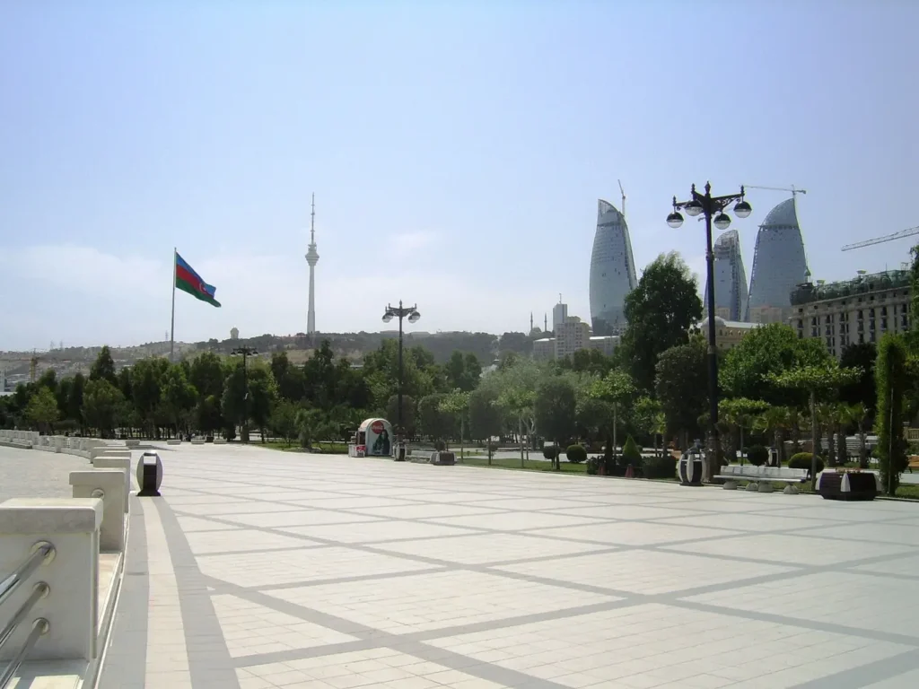 The paved seafront boulevard in Baku with the national flag and the Flame Towers