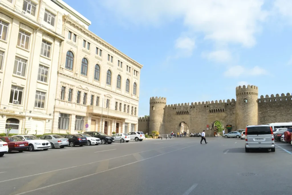 The fortress gate into the Old City of Baku with cars parked along the street