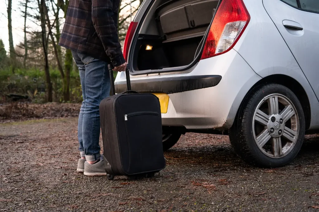 Loading a suitcase into the open boot of a hatchback