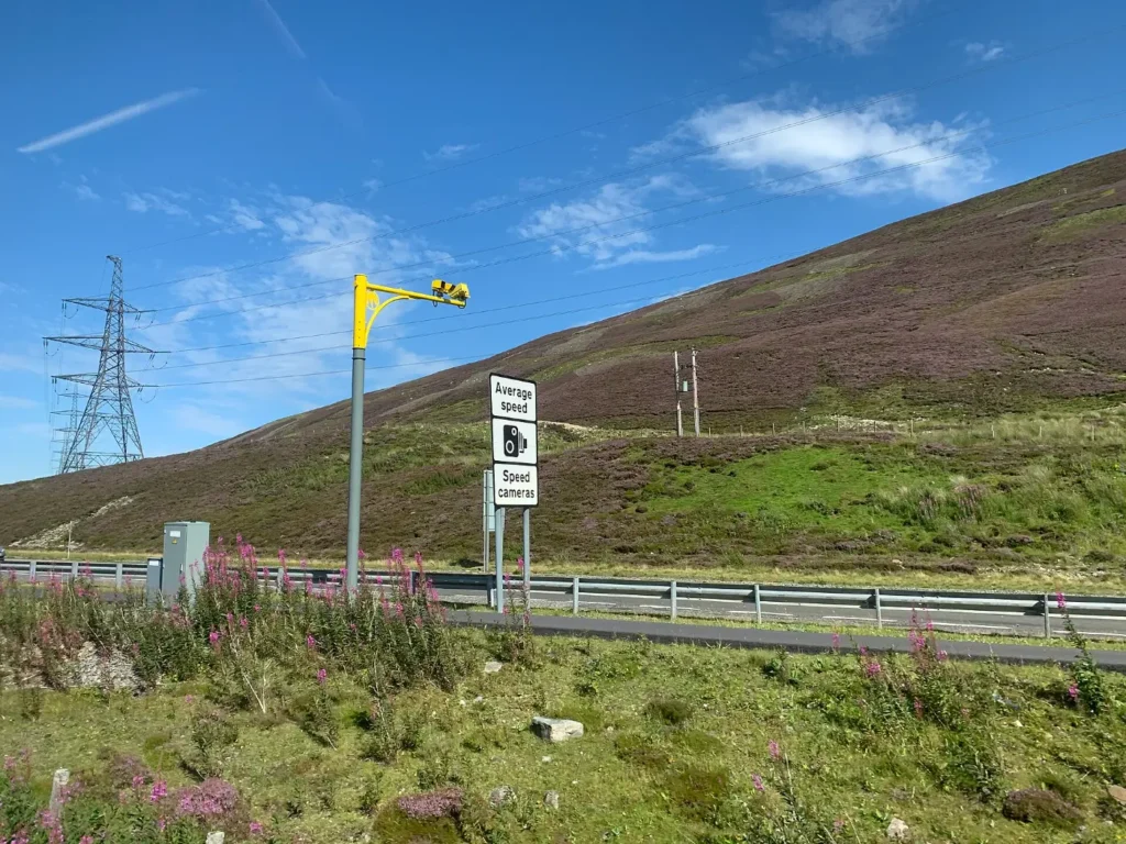 A speed camera on a pole beside a highway